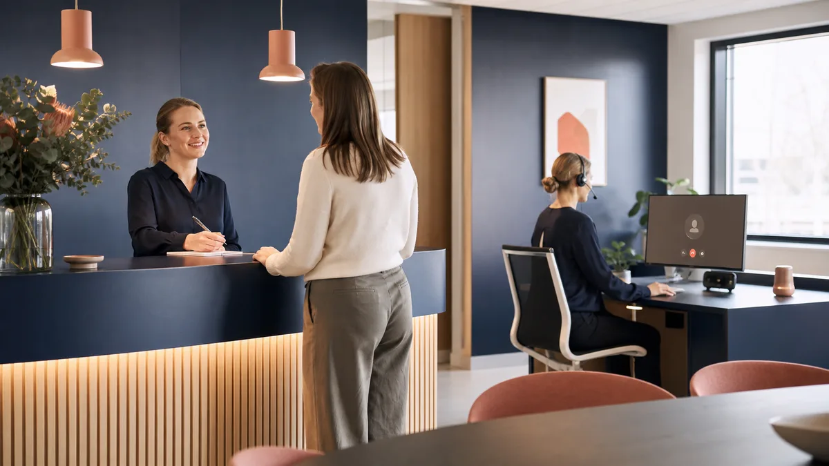 Delt scene med dansk receptionist og digital AI-assistent i samme kundeserviceflow