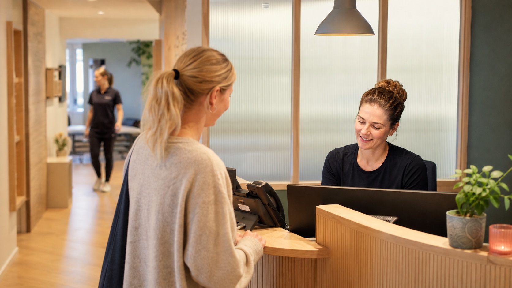 Receptionist hjælper en patient ved skranken i en rolig skandinavisk klinik